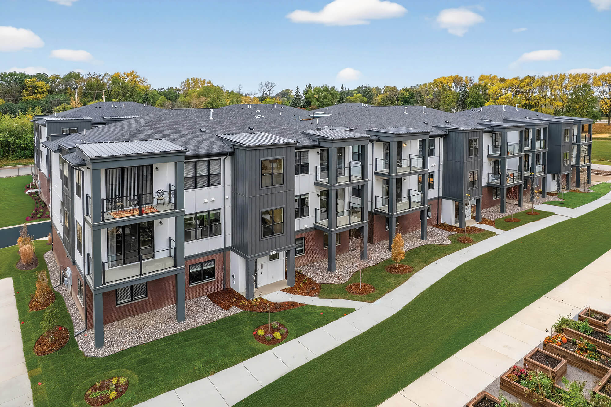 Modern three-story building with gray and white exterior and green landscaped grounds.