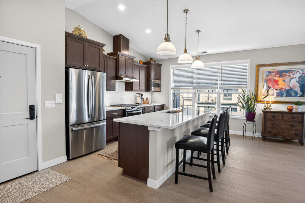 Modern kitchen with wood cabinets, stainless steel appliances, and a white island.